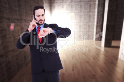 Composite image of serious businessman checking the time while o