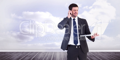 Composite image of businessman talking on phone holding laptop