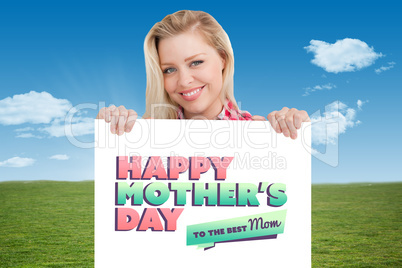 Composite image of woman beaming while holding a blank sign