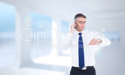 Composite image of businessman on the phone looking at his wrist