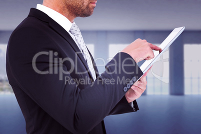 Composite image of businessman using his tablet pc