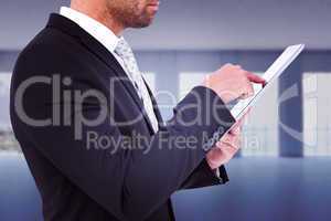 Composite image of businessman using his tablet pc