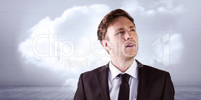 Composite image of young businessman thinking and looking up