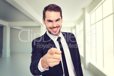 Composite image of happy businessman pointing at camera