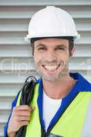 Composite image of happy electrician with wire against white bac