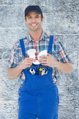 Composite image of confident plumber holding sink pipe