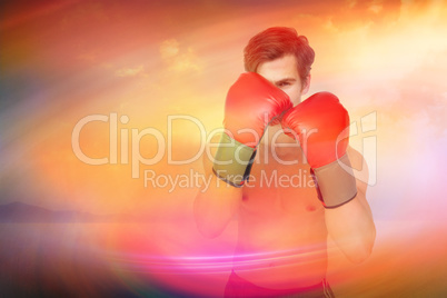 Composite image of muscly man wearing red boxing gloves in guard