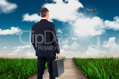 Composite image of businessman in suit looking through binocular