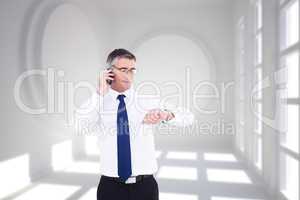 Composite image of businessman on the phone looking at his wrist