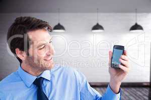 Composite image of smiling businessman showing smartphone to cam