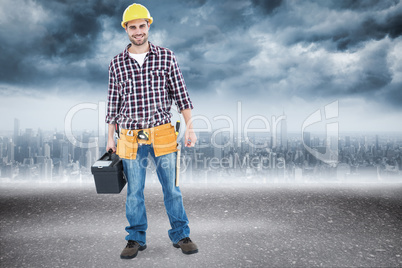 Composite image of happy male hanyman carrying toolbox