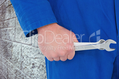 Composite image of mechanic holding spanners on white background