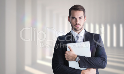 Composite image of businessman in suit posing with his laptop