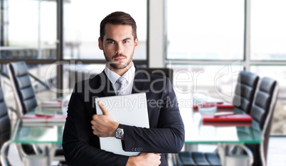 Composite image of businessman in suit posing with his laptop