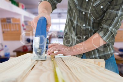 Composite image of carpenter cutting wooden plank with electric