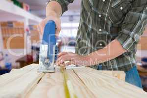 Composite image of carpenter cutting wooden plank with electric
