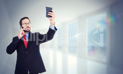 Composite image of businessman holding calculator while talking