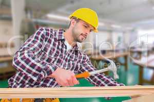 Composite image of handyman using hammer on wood