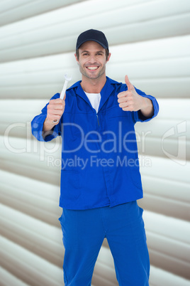 Composite image of happy mechanic holding spanner