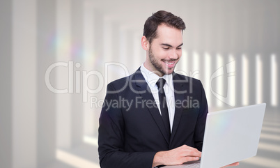 Composite image of smiling businessman standing and using laptop