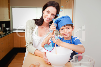 Composite image of mother and son having fun preparing dough