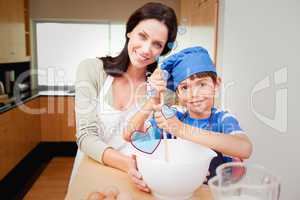 Composite image of mother and son having fun preparing dough
