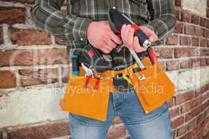 Composite image of manual worker holding gloves and hammer power