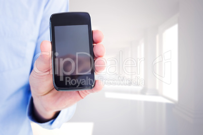 Composite image of businessman showing his smartphone to camera