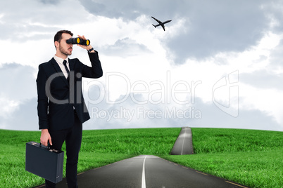 Composite image of businessman holding a briefcase while using b