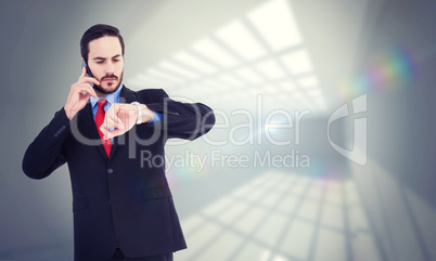 Composite image of serious businessman checking the time while o