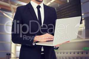 Composite image of mid section of a businessman using laptop