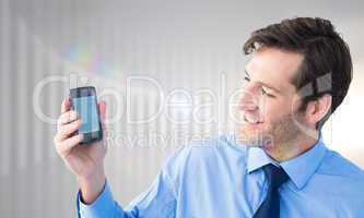 Composite image of smiling businessman showing smartphone to cam