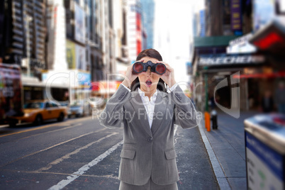 Composite image of surprised businesswoman looking through binoc