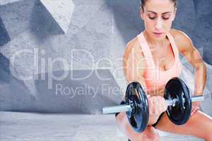 Composite image of strong woman doing bicep curl with large dumb