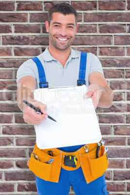 Composite image of smiling handyman giving clipboard for signatu