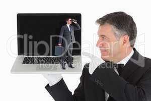 Composite image of businessman looking through binoculars