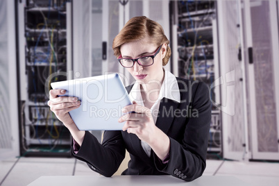 Composite image of redhead businesswoman using her tablet pc