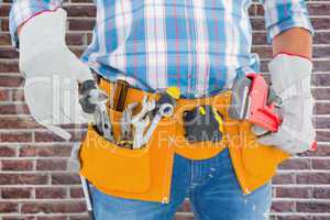 Composite image of midsection of handyman holding hand tools