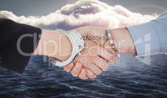 Composite image of business people in handcuffs shaking hands