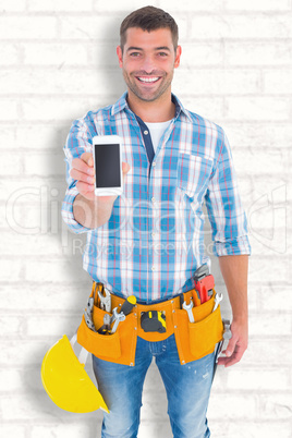 Composite image of portrait of smiling handyman showing mobile p