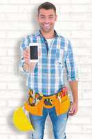 Composite image of portrait of smiling handyman showing mobile p
