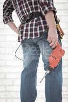 Composite image of male handyman holding drill machine