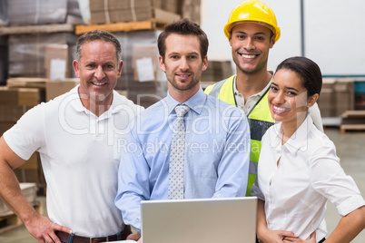 Warehouse managers and worker smiling at camera