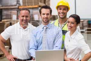 Warehouse managers and worker smiling at camera