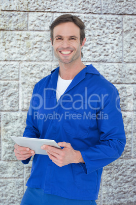 Composite image of handsome mechanic holding digital tablet