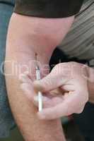 Man injecting himself with a small hypodermic