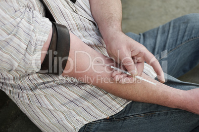 Man injecting himself with a small hypodermic