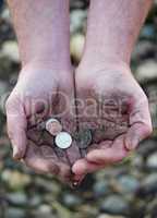 Dirty cupped hands holding few coins