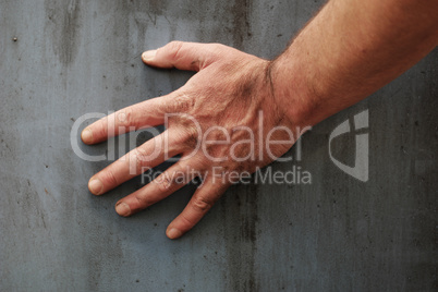 Male hand touching the surface of a concrete wall