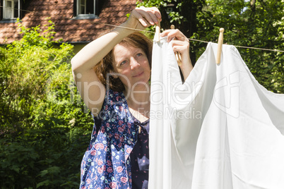 Frau beim Wäscheaufhängen im Garten, Hanging up the washing in